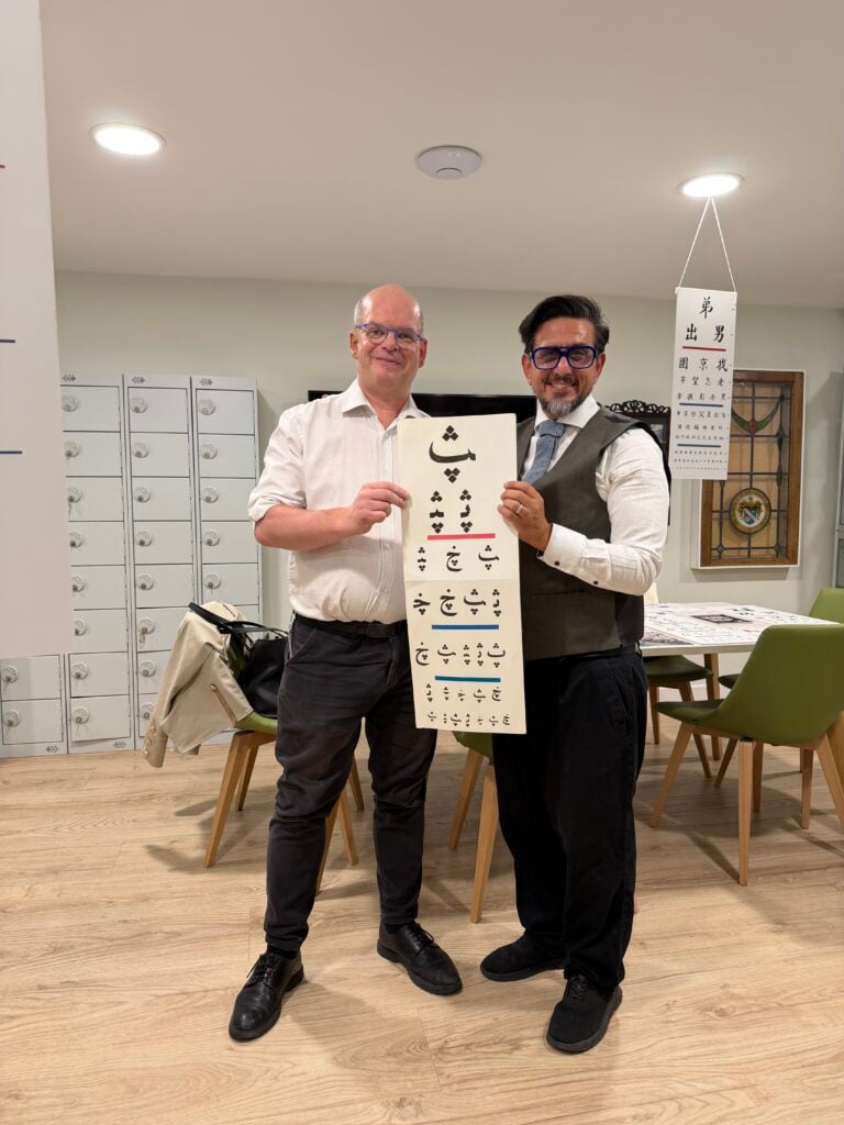 Garry Kousoulou FBDO with an optician holding a test chart during a practice visit
